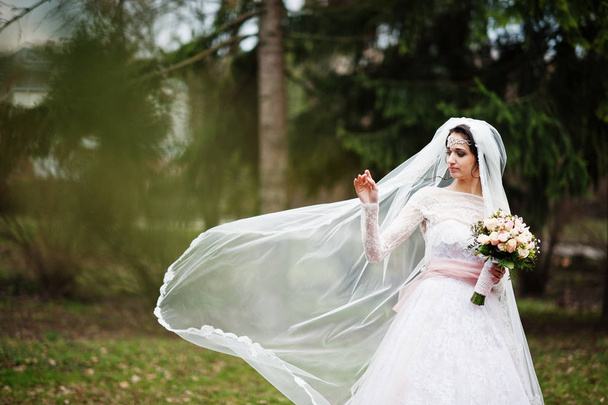 Portrait of a pretty bride posing in the park with a bouquet on  - Фото, зображення