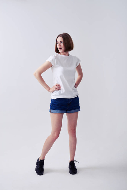 Beautiful woman posing in jeans shorts and white T-shirt - Foto, afbeelding