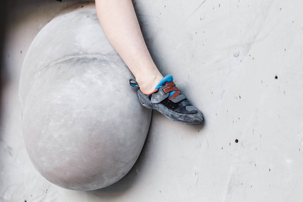 人工岩壁ジムのスポーツマンの登山者の足。クローズ アップ ビュー - 写真・画像