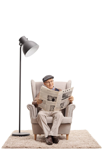 Elderly man reading a newspaper in an armchair - Photo, Image