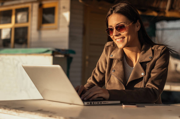 Девушка в солнечных очках работает с ноутбуком
  - Фото, изображение