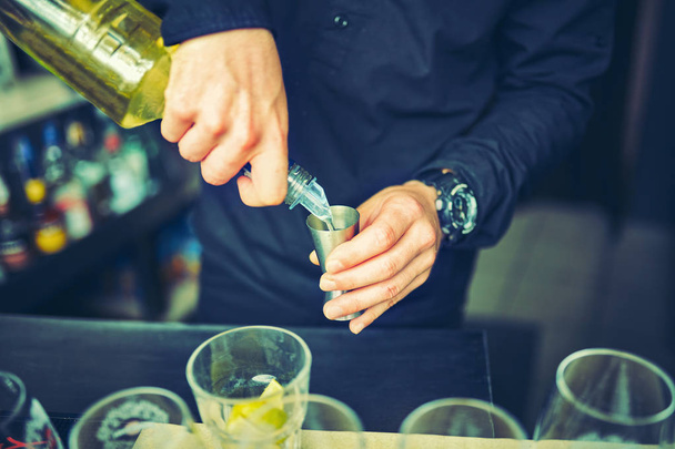 Charming barman pours alcohol from a bottle into a jigger - Foto, Imagem