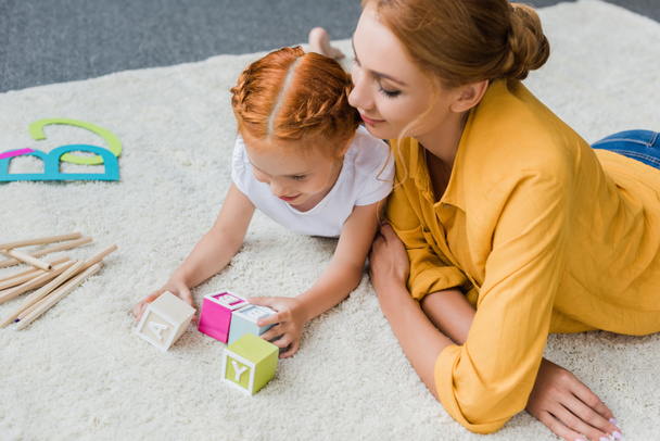 mother and daughter playing with letter cubes - Фото, изображение