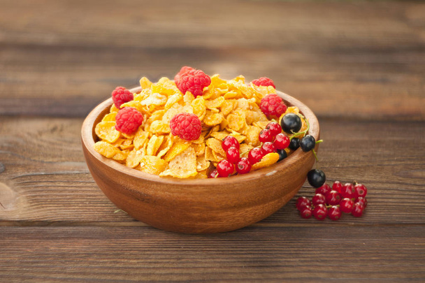 Завтрак из кукурузных хлопьев с ягодами в деревянной чаше
 - Фото, изображение