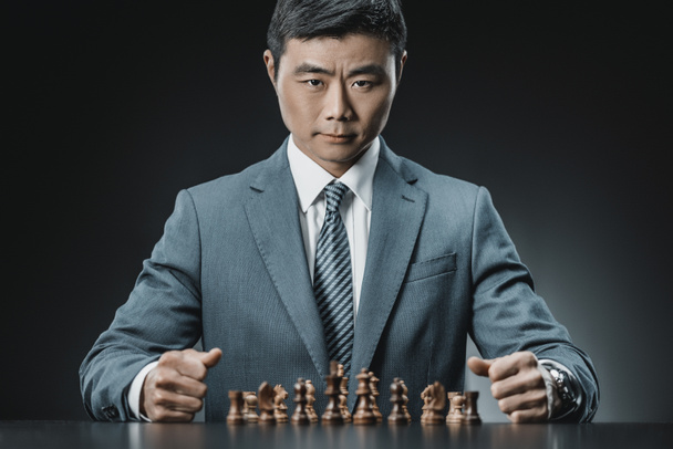 азиатский бизнесмен и шахматные фигуры
 - Фото, изображение