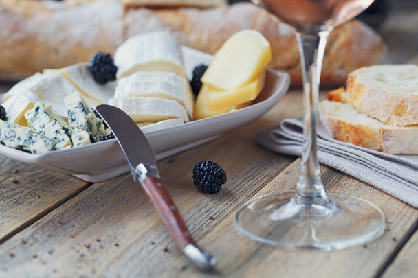 Cheese plate. Assortment of cheese with berries and glass of ros - Fotó, kép