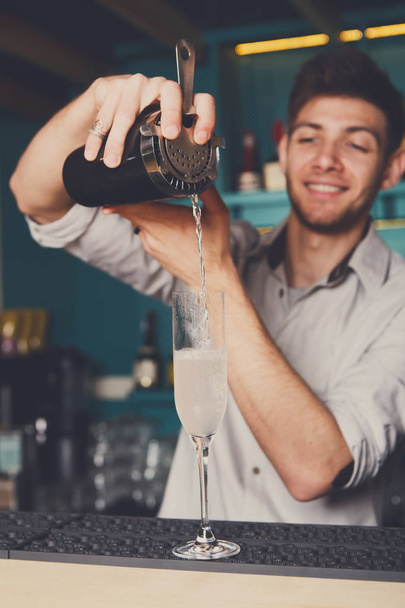 Camarero joven vertiendo bebida de cóctel en el vaso
 - Foto, Imagen