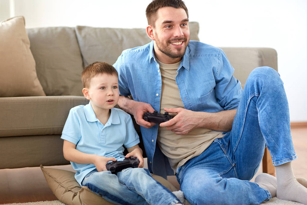 father and son playing video game at home - Foto, Bild