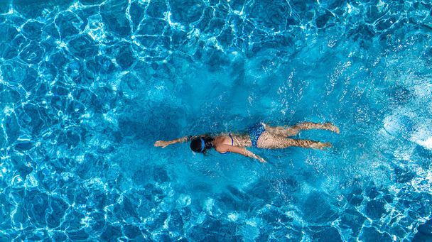 Aerial top view of woman in swimming pool water from above, tropical vacation holiday concept - Фото, изображение
