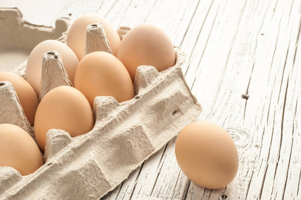 chicken eggs in cardboard box on white wooden background - Foto, Imagen