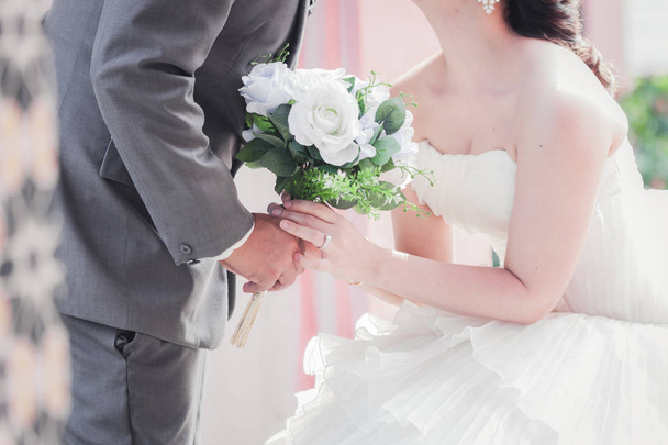 Braut und Bräutigam halten Händchen und einen Strauß schöner Blumen - Foto, Bild