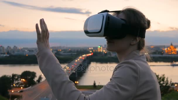 Vrouw maakt gebruik van virtual reality-bril in de stad na zonsondergang - Video