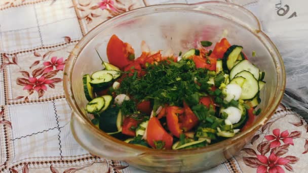 Salade met tomaten, peren en greens is op de tafel in de tuin. De hand snijdt de salade. Een gezonde salade groenten. Picknick buiten het huis. - Video