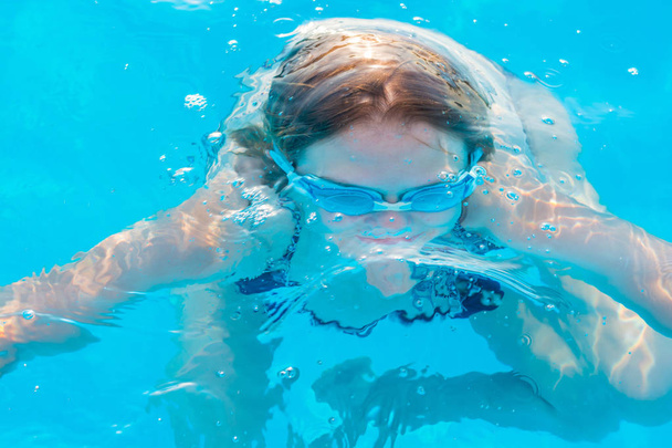 Niña bucea en la piscina con gafas para nadar
 - Foto, Imagen