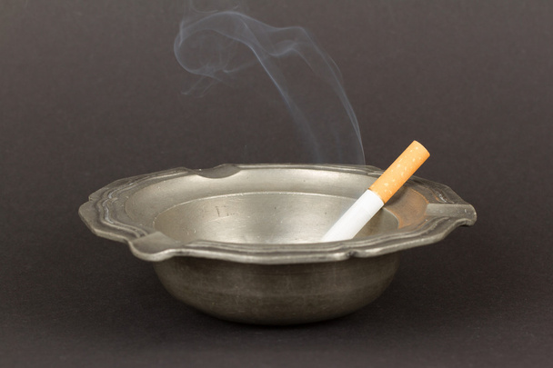 Burning cigarette in an old tin ashtray - Photo, Image