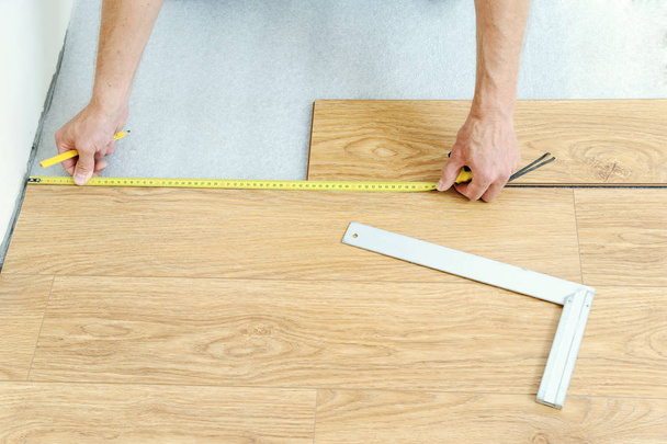 Installation of a laminate floorboard. - Фото, изображение