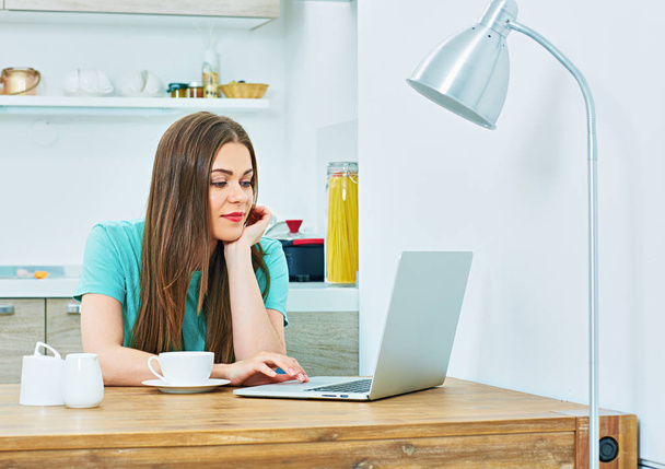 woman with laptop sitting in kitchen - Fotografie, Obrázek