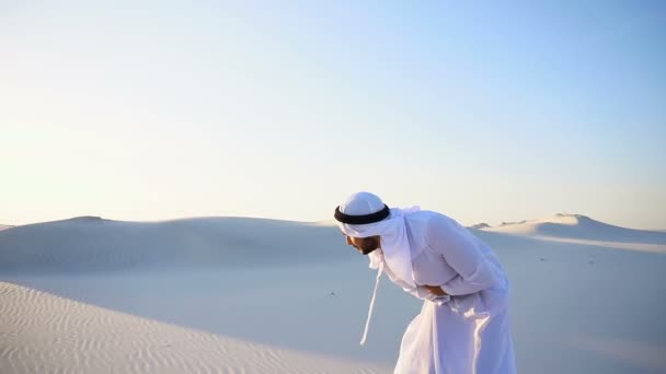 Jonge mannelijke emiraat lijdt aan ernstige pijn in buik, staande in het midden van de zandwoestijn op warme zomerdag. - Video