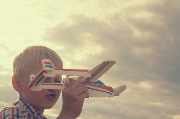 The boy with his hand runs the model of the plane into the sky. - Photo, Image