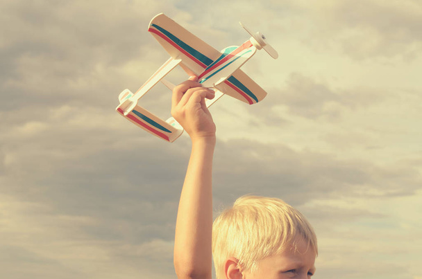 Το αγόρι με το χέρι το μοντέλο του αεροπλάνου τρέχει στον ουρανό. - Φωτογραφία, εικόνα
