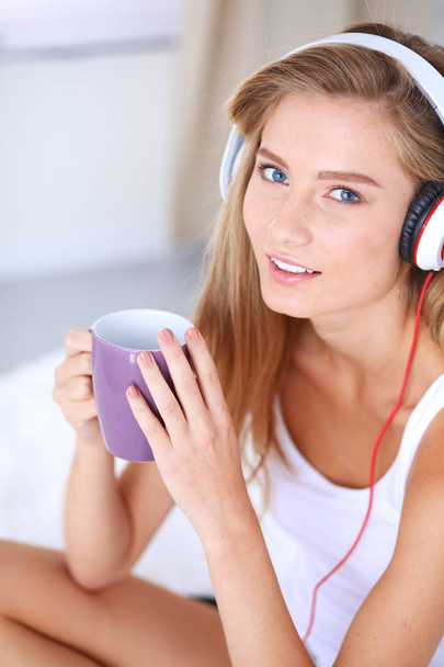 Portrait of beautiful woman in morning listening music sitting on bed at home. Portrait of beautiful woman - Фото, изображение
