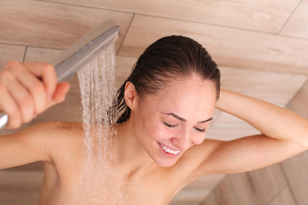 Young beautyful woman under shower in bathroom. - Fotografie, Obrázek