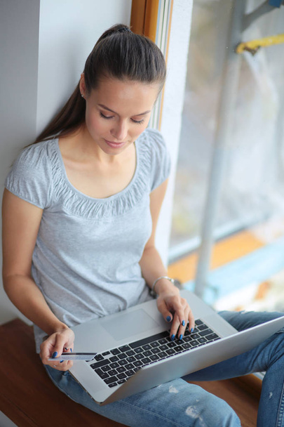 Young beautiful woman using a laptop computer at home. Young beautiful woman. - Фото, зображення