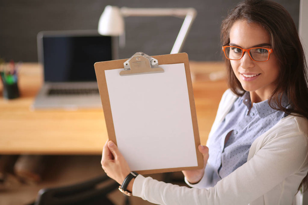 Young woman standing near desk with laptop holding folder and cup of coffee. Workplace. Business Woman. - Foto, Imagen