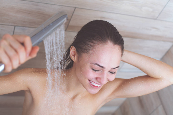 Young beautyful woman under shower in bathroom. - Fotoğraf, Görsel