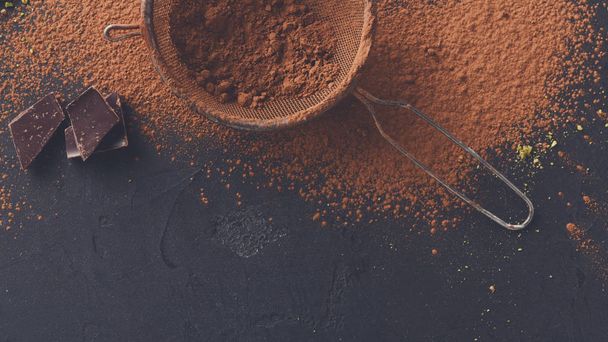 Какао-порошок у ситі на фоні чорного шиферу
 - Фото, зображення