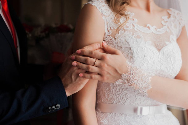 The bride and groom holding hands. Hands newlyweds close-up. The groom embraces the bride. Wedding day - 写真・画像