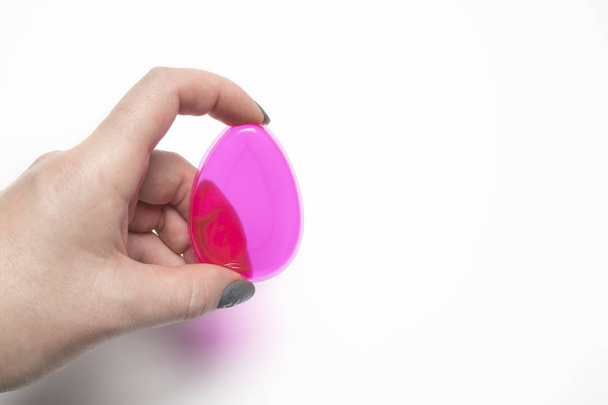 Woman hand holding silicone foundation sponge on a white backgro - Foto, afbeelding