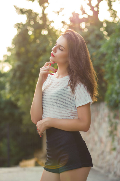 Vonzó fiatal modell az elegáns ruhákat, a parkban, a naplemente - Fotó, kép