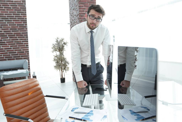 serious businessman standing near the desktop - Foto, Imagen