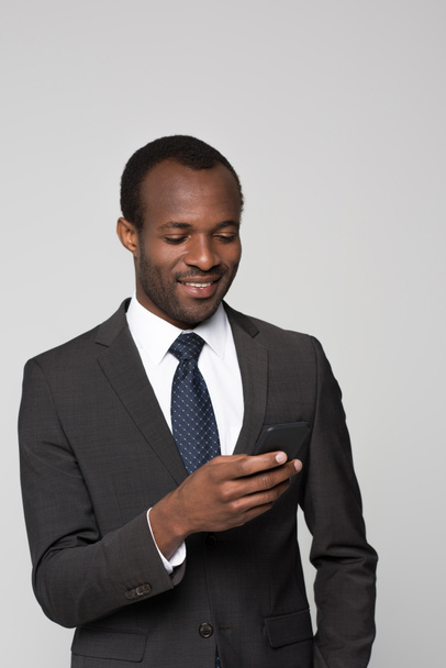 Smiling businessman looking at smartphone - 写真・画像