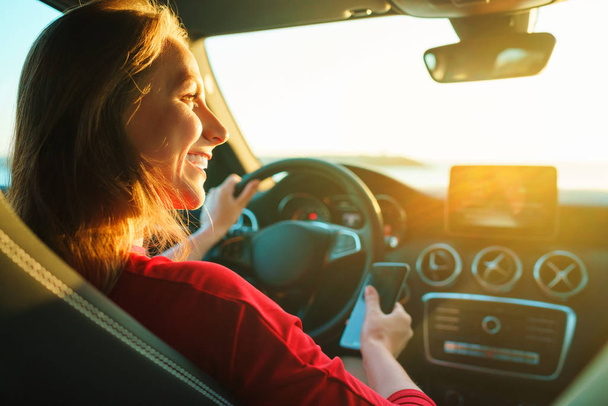 Szczęśliwa kobieta używa smartfona podczas jazdy samochodem - Zdjęcie, obraz