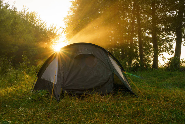 Toeristische tenten op rivieroever bij zonsopgang - Foto, afbeelding