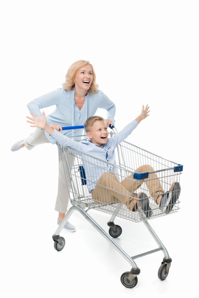 mother riding son in shopping cart - Фото, зображення