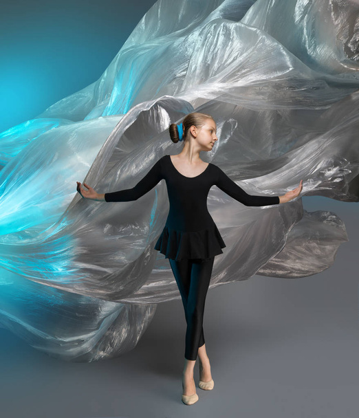 Girl in black clothes in the studio on the background of flying polyethylene film - Φωτογραφία, εικόνα