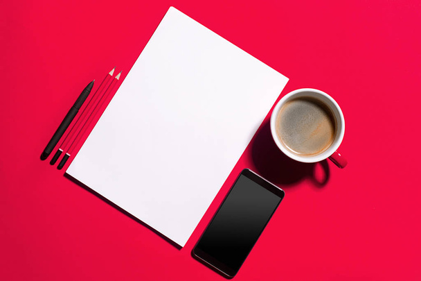 Modern red office desk table with smartphone and cup of coffee. - 写真・画像