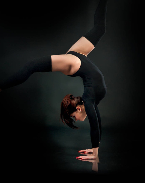 Beautiful flexible young gymnast athlete woman in black leotard  - 写真・画像
