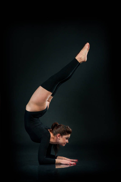 La belle femme de fitness faisant de l'exercice d'étirement sur fond noir Mains debout à l'envers
 - Photo, image