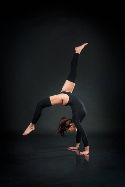 hermosa mujer flexible haciendo elementos acrobáticos en respaldo negro
 - Foto, Imagen