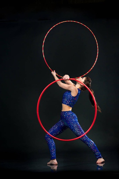 gymnast doing gymnastics exercises with colorful hoop on a black - Photo, Image