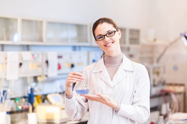 Woman scientist in laboratory with beaker posing - 写真・画像
