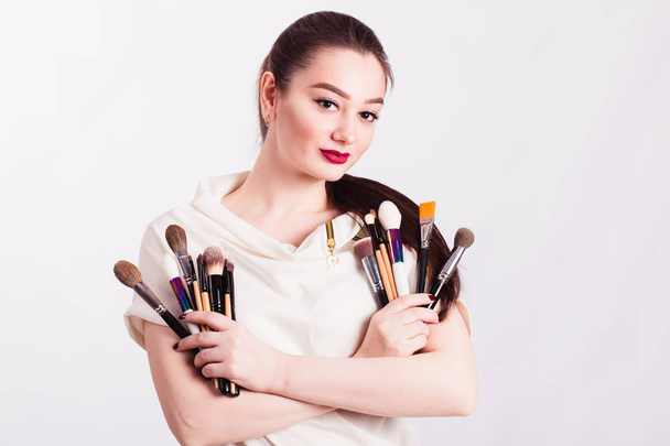Makeup artist with brushes in hand on a white background - 写真・画像