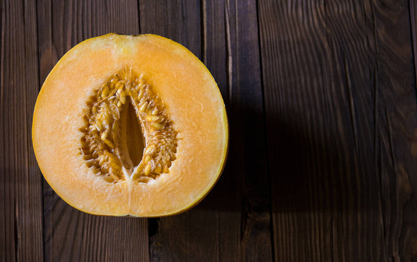 Melon cut in half on a wooden background (Top view) - Photo, Image
