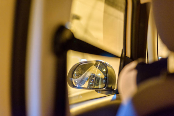 Вид на левое зеркало автомобиля с заднего сидения в туннеле
 - Фото, изображение