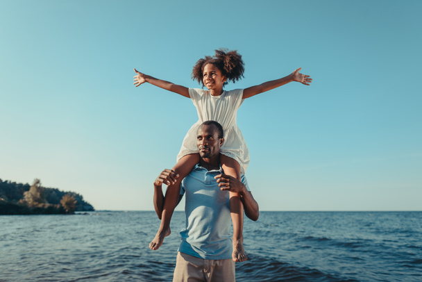 africano americano padre llevar hija en playa
 - Foto, Imagen