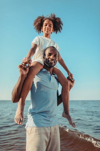 père afro-américain portant fille sur la plage
 - Photo, image